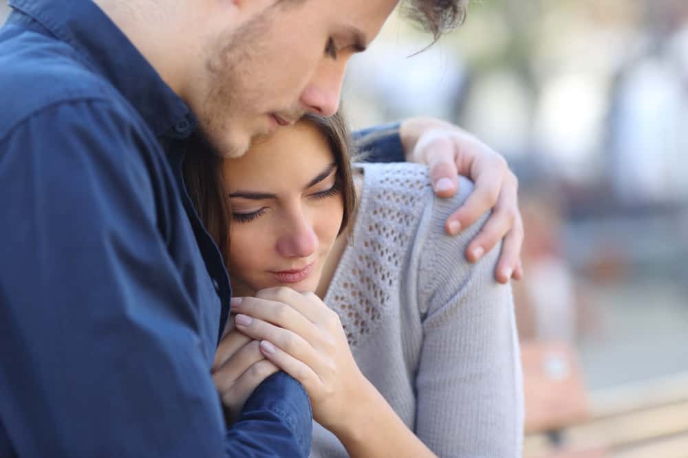 A man embraces a woman outdoors.