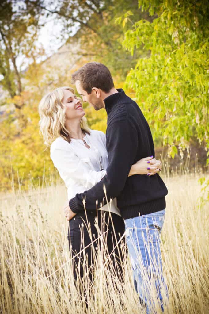 A couple embraces one another in a field.