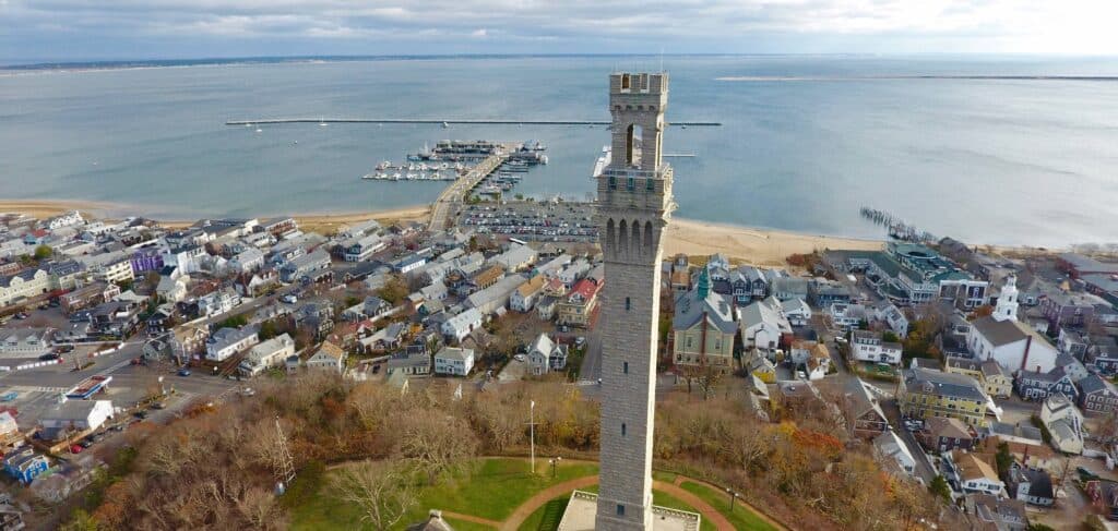 A tall fort-like structure with a town next to it near the water.