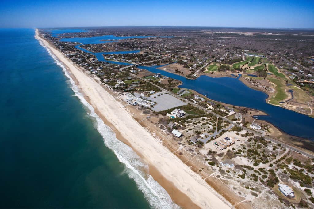 Aerial view of an island town where waves crash against the beach.