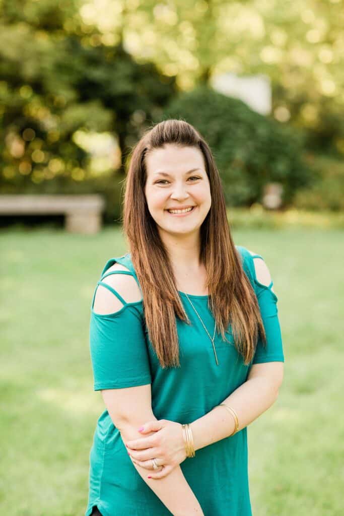 A woman smiles with a garden behind her.