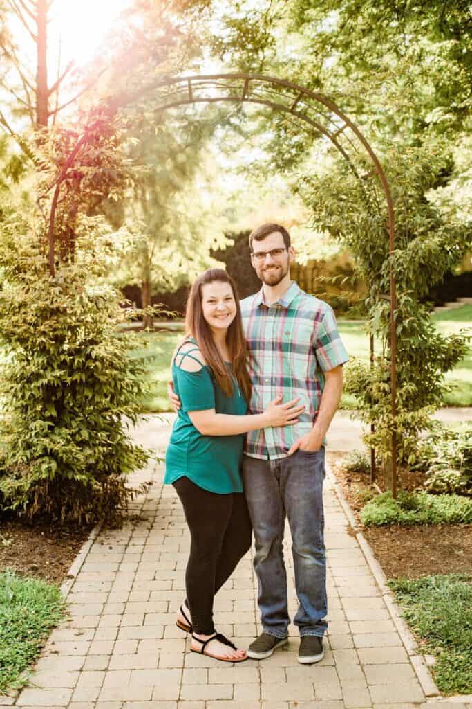 A couple stands in a garden.