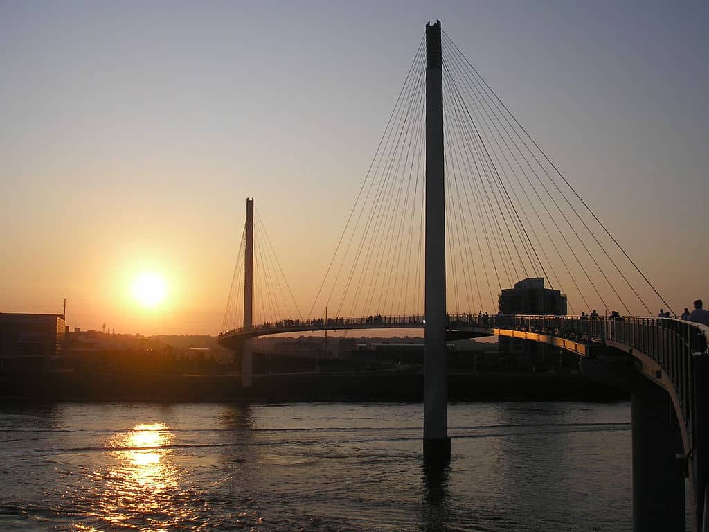 The sun setting over a bridge that stretches across the water.