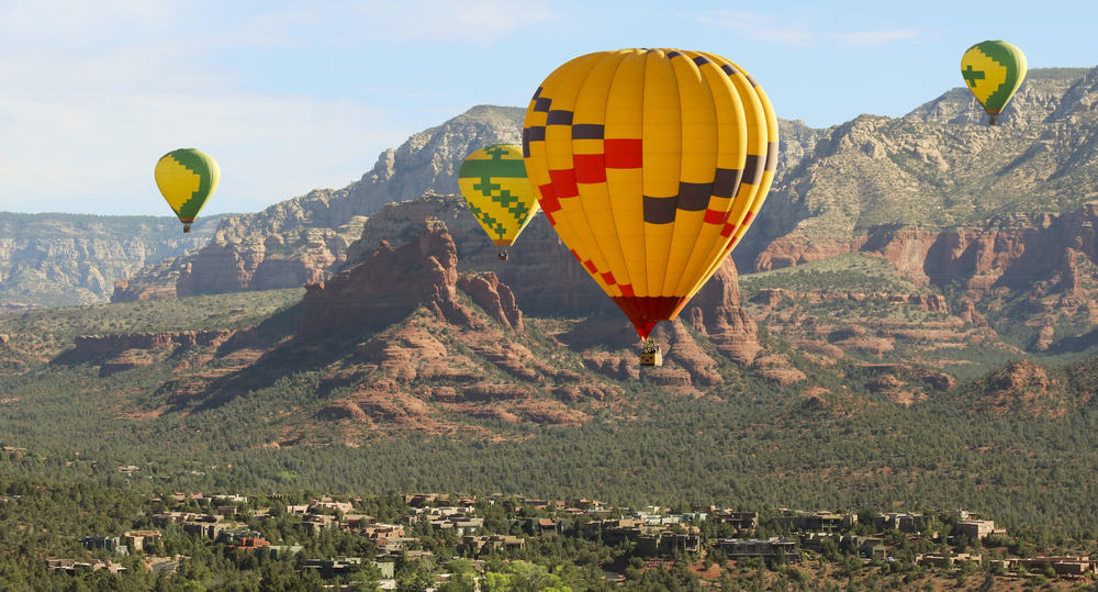 Four hot air balloons float high over a town in the desert.