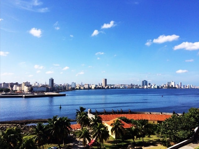 A body of water is in front of a city skyline under a blue sky.