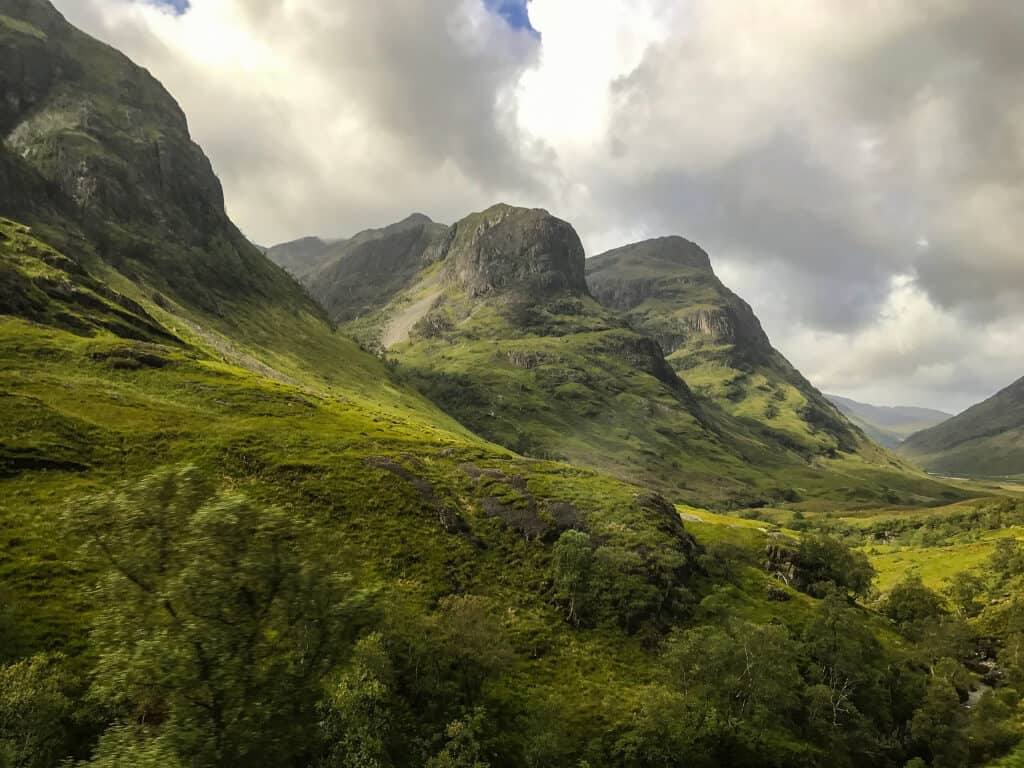 Three large mountains covered in greenery.