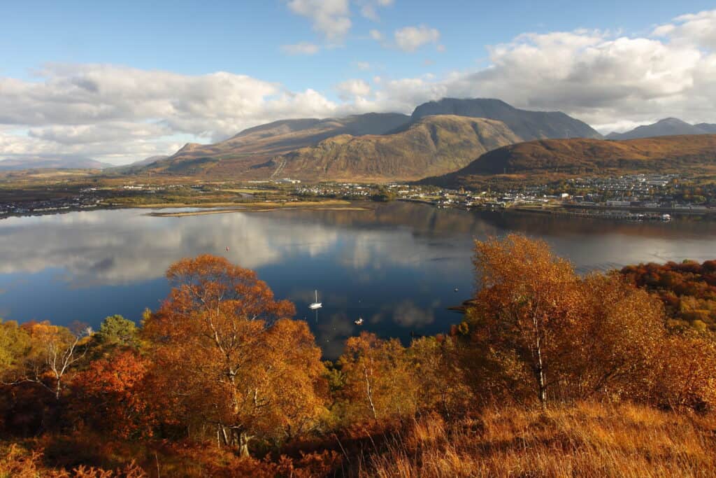 A calm lake sits surrounded by mountains in the fall.