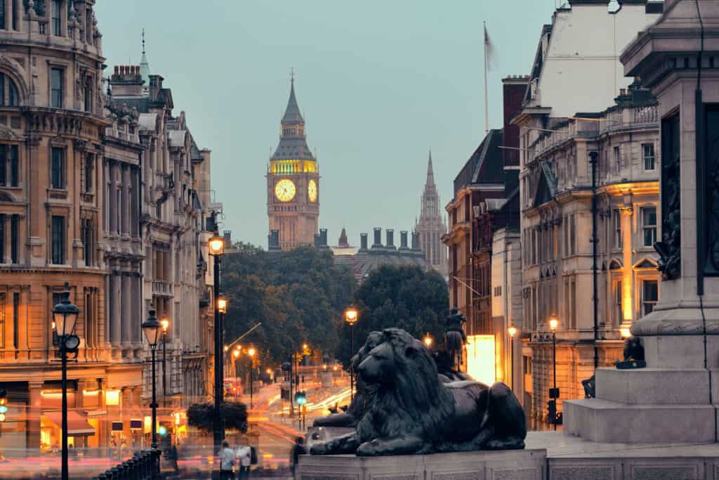 A lion statue stands tall on a street lined by historic buildings.