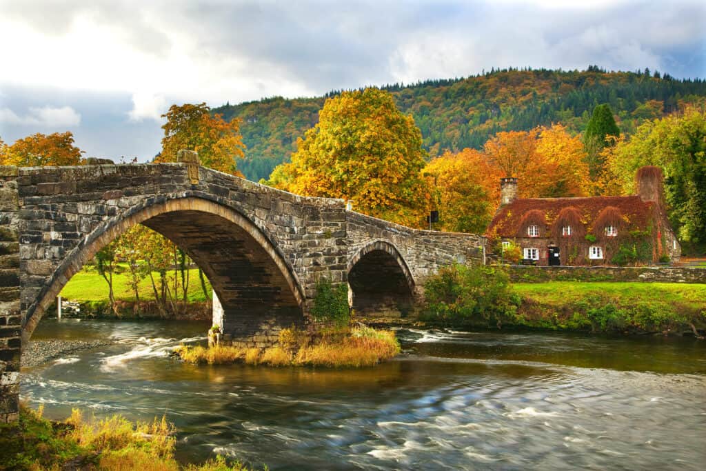 A brick bridge stretches across a lake in fall.