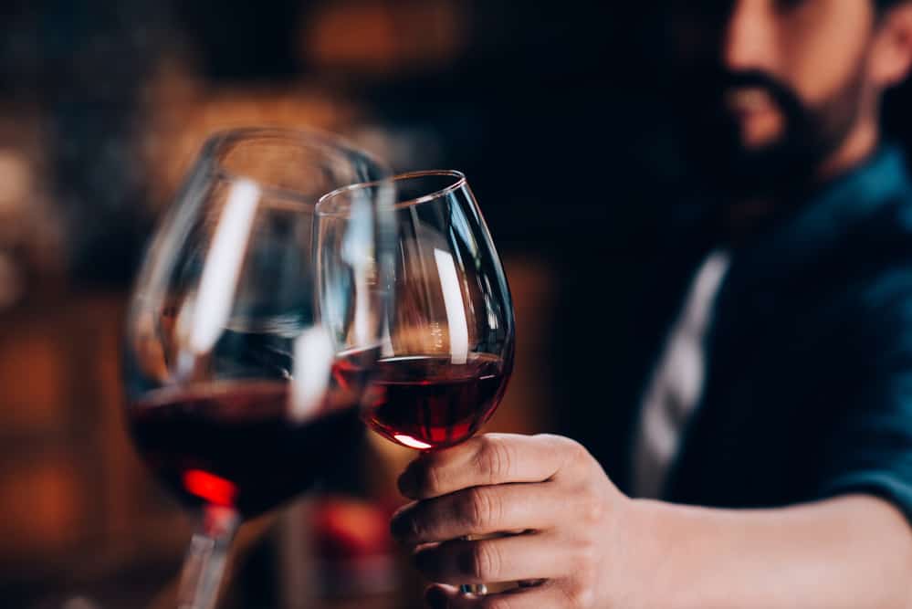 Two people toast their glasses of red wine