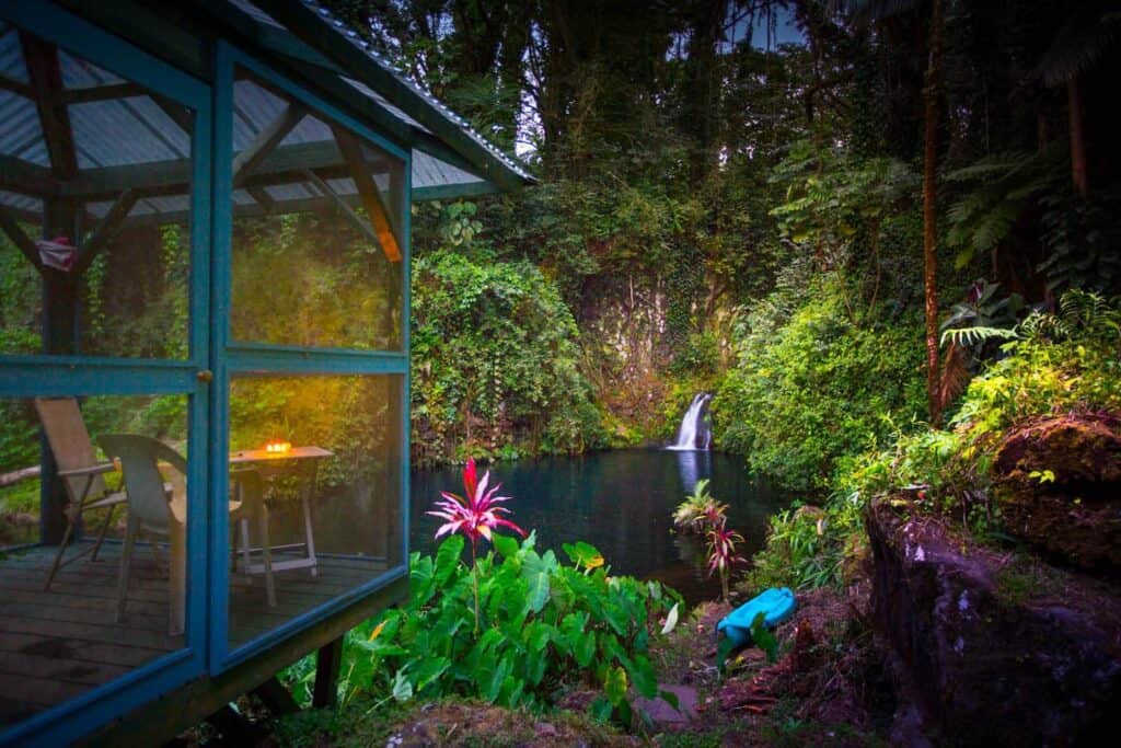 A small waterfall leads into a lake surrounded by lush greenery.