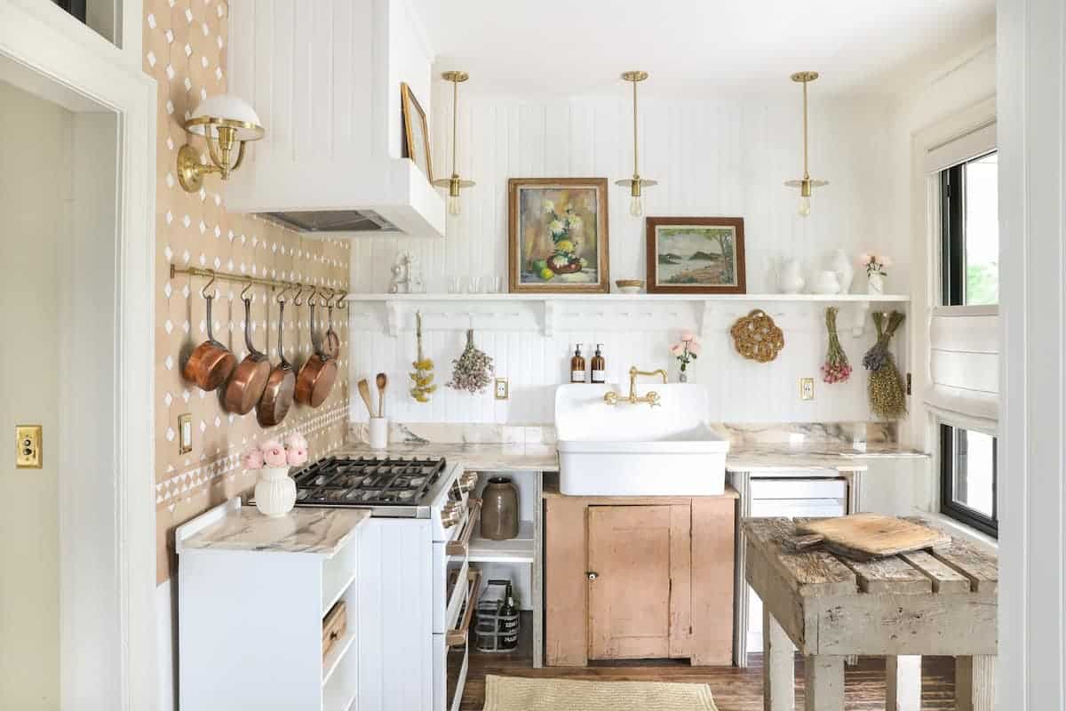 A kitchen with brass pots hanging on the wall.