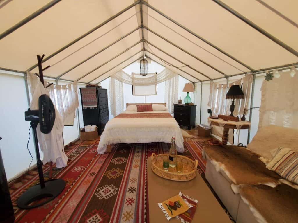 A bed is made in a tent with boho southwestern themes.