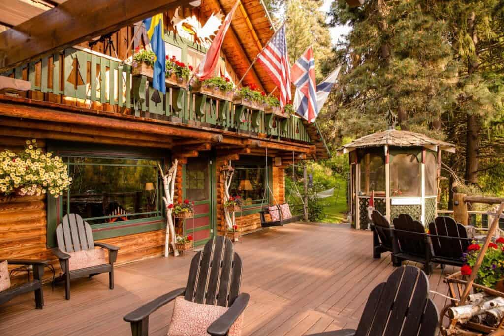 A patio is lined with chairs next to an alpine cabin.