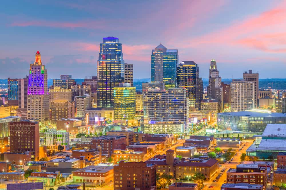 A city skyline is lit up at night under a purple and pink sky.