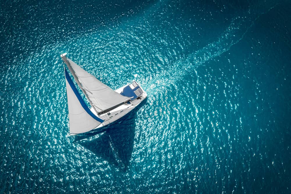 Aerial view of a white sailboat on a blue ocean.