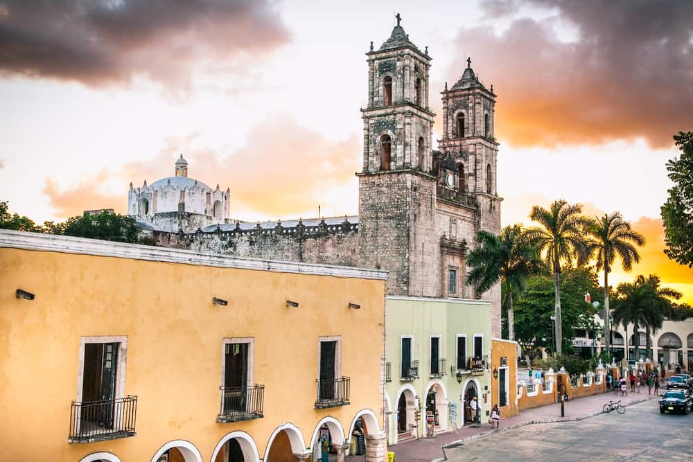 The sun sets over a town with colorful buildings and a tall church.