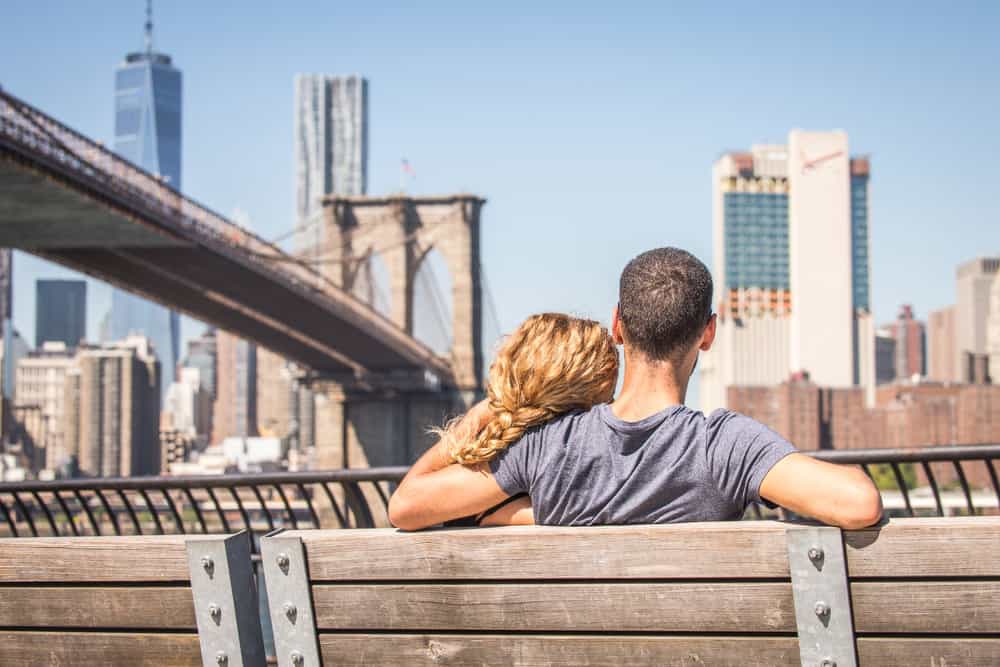 A couple sits and gazes at architecture while sitting on a bench.