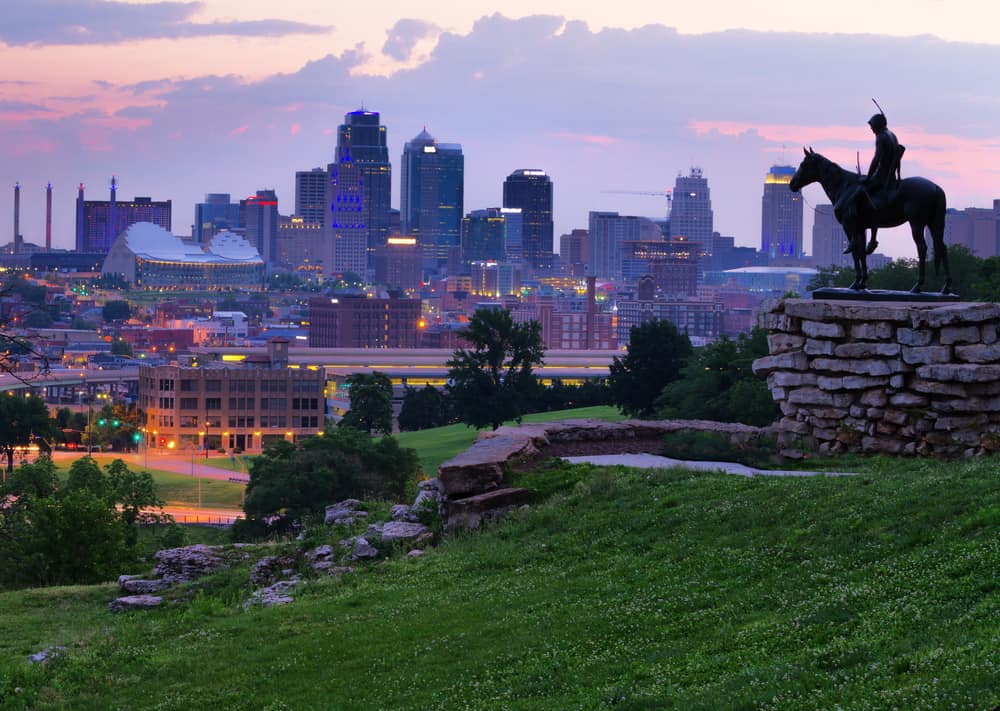 A man riding a horse sculpture is seen looking out at a city skyline.