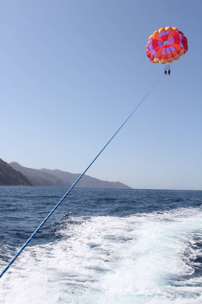 A man is floating above water by mountains.