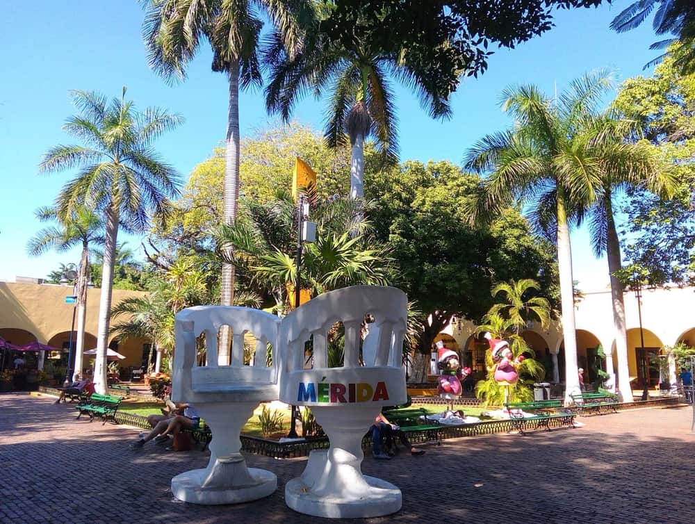 White chairs in a plaza say \"Merida\" on the back.