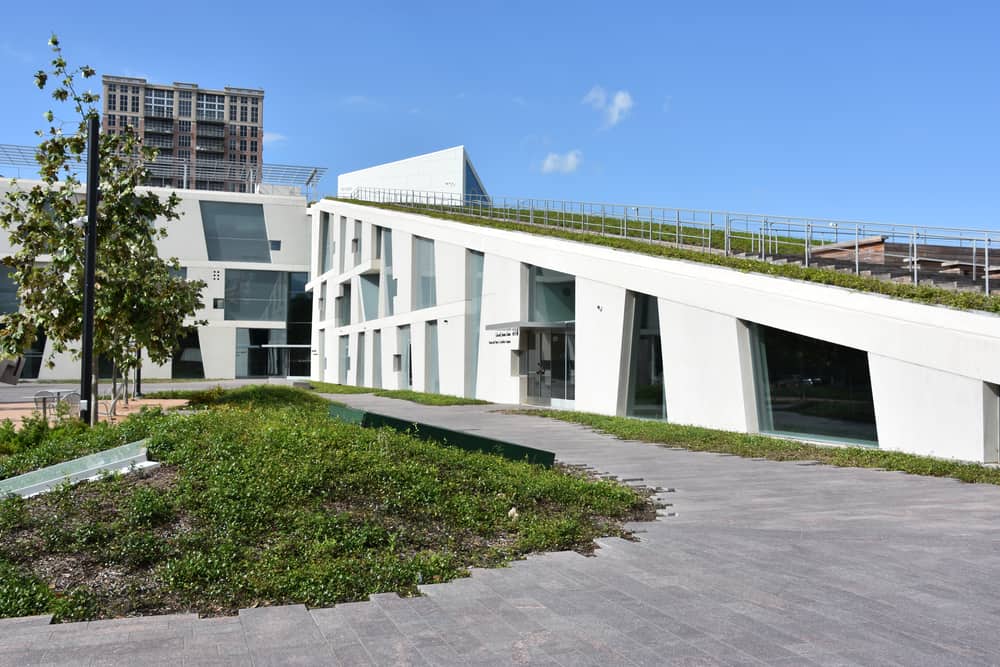 White building with funky architecture surrounded by greenery.