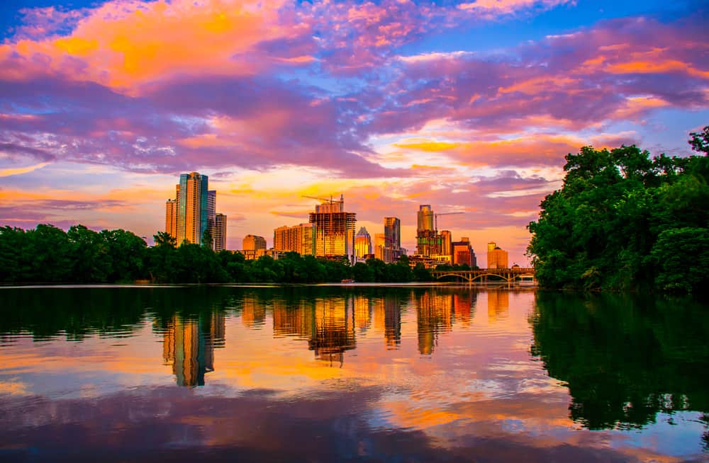 A skyline is reflected on the lake below at sunset.