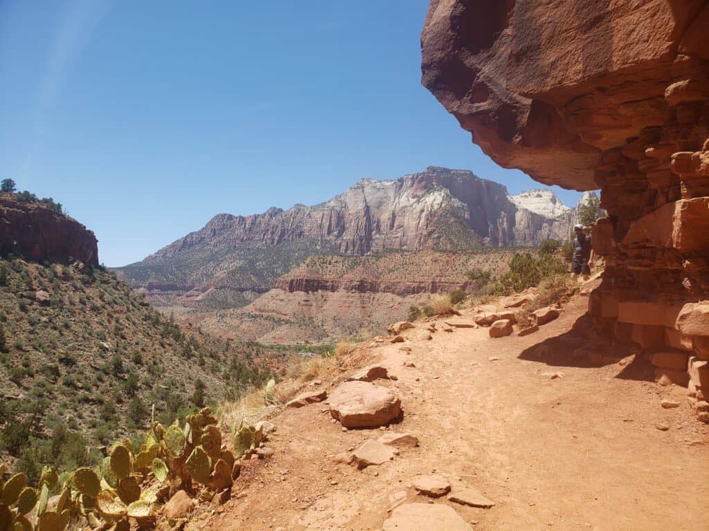 A small hiking path leading around a red rock formation. 