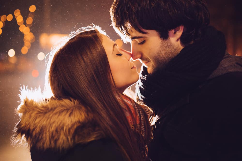 A couple leans in for a kiss in winter.