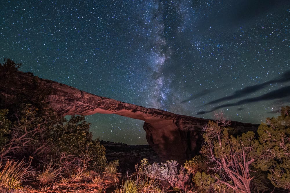 A starry sky is seen over a rock formation.