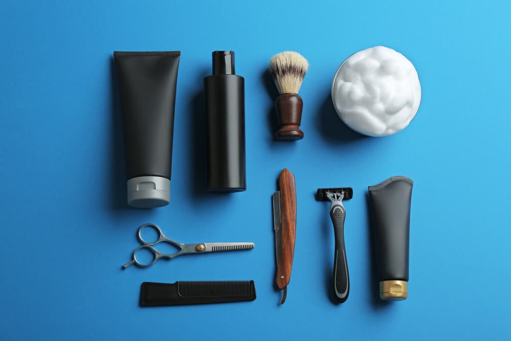 A flatlay of mens grooming items on a bright blue background.