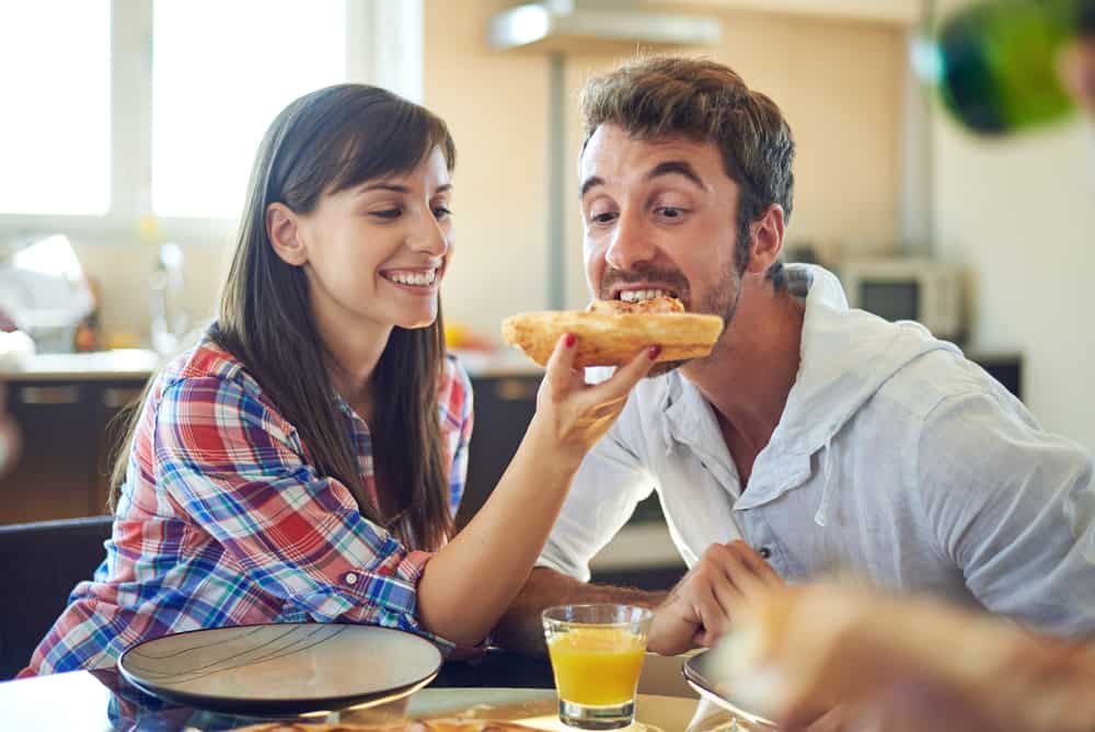 A woman feeds a man breakfast.