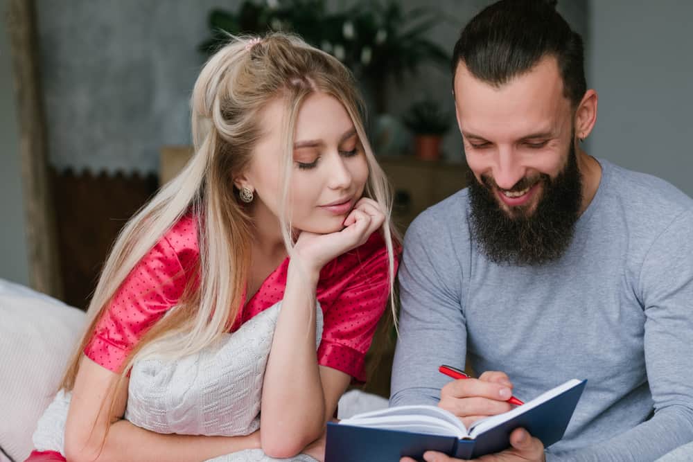 Happy couple writing in best journals for couples