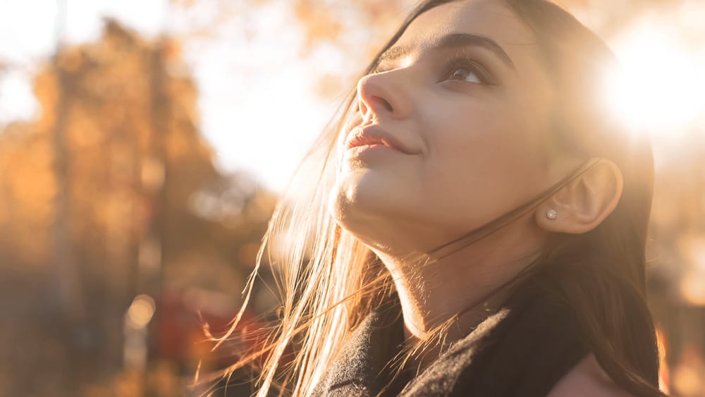 A woman looks up to the sky with a smile on her face.