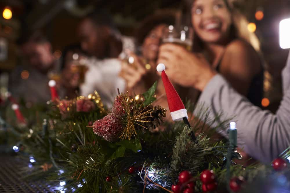 Close up of Christmas decorations. In the background, friends can be seen drinking and having a jolly time.