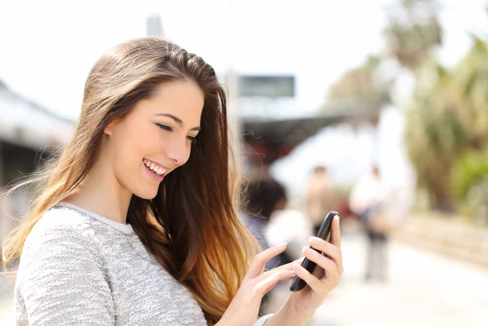 A woman smiles while reading a text.