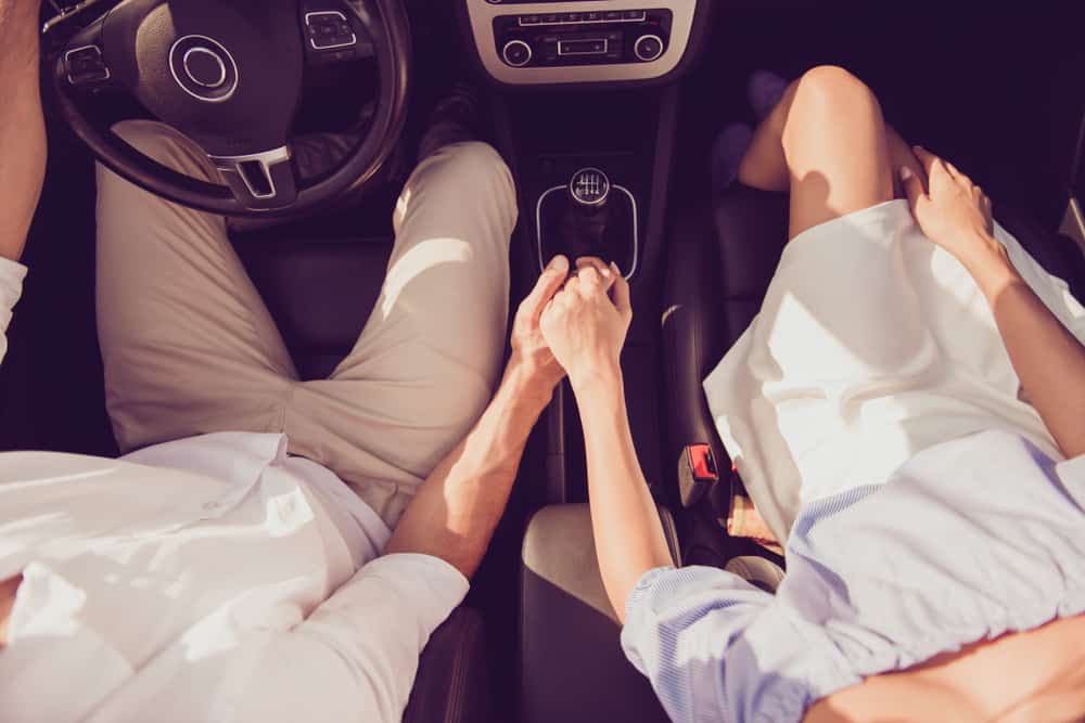 Aerial view of a couple holding hands in a car.