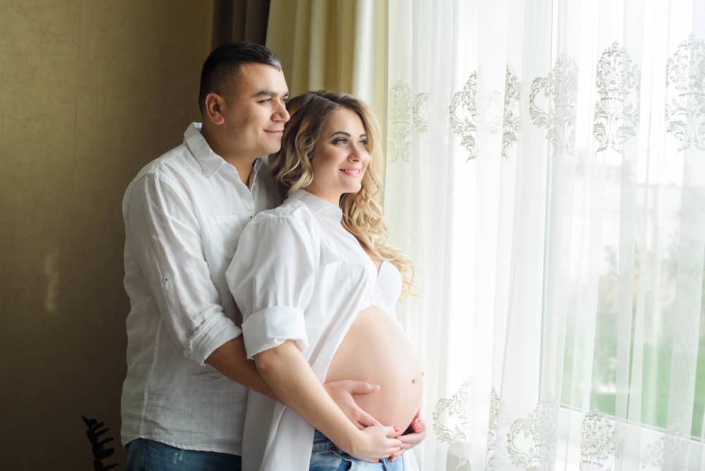 Pregnant couple looking out of window on a luxury babymoon