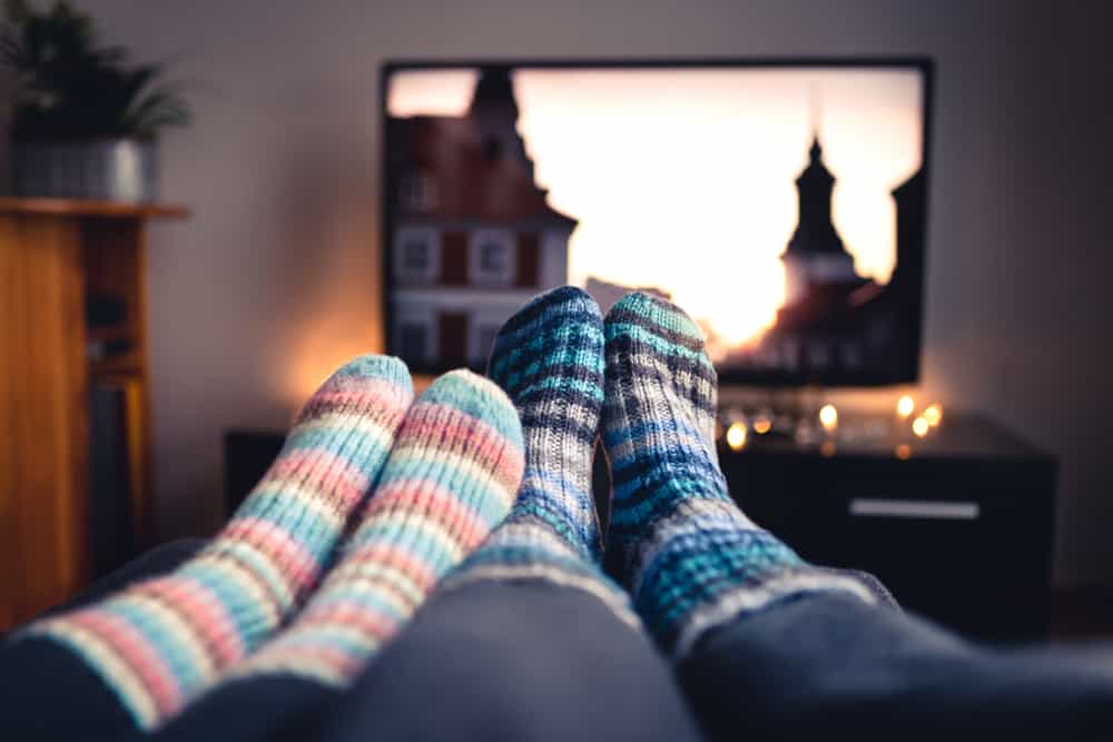Couples feet as they watch a movie on a television.