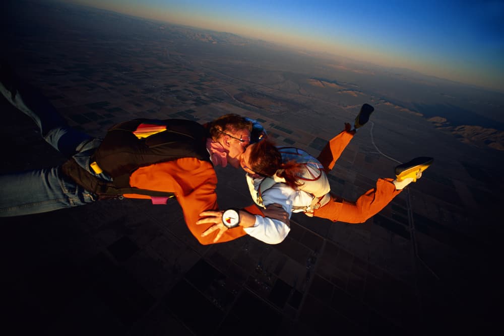 A couple kisses while skydiving.