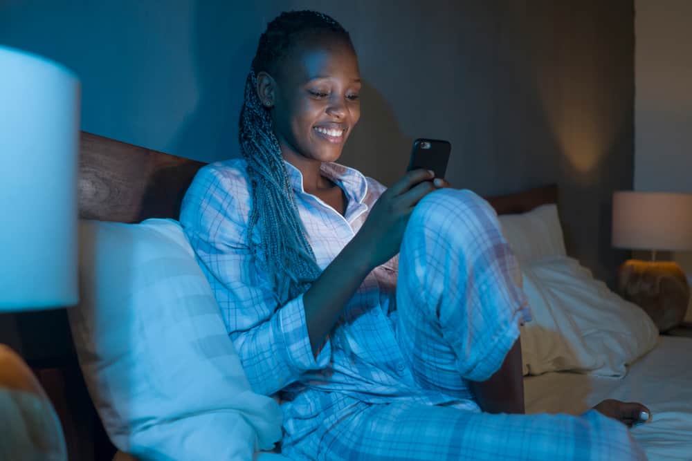 Woman in bed smiling reading goodnight text messages to woman