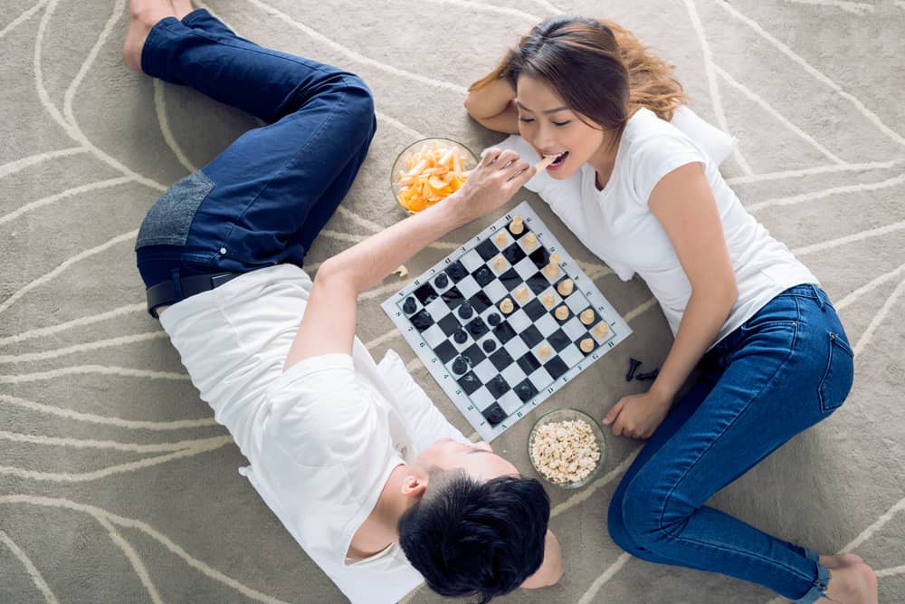 A man feeds a woman a snack while they play a game together.