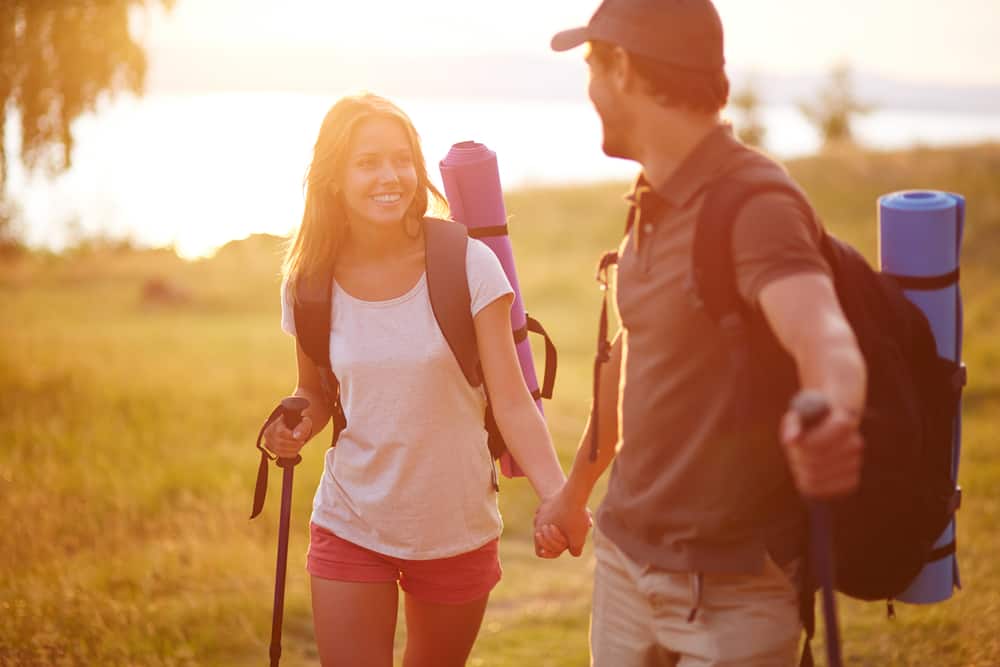 A couple holds hands while hiking outdoors.