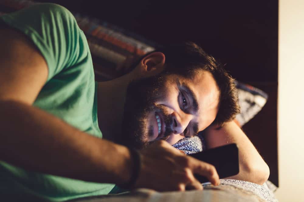 Man lying in bed reading good night messages for him