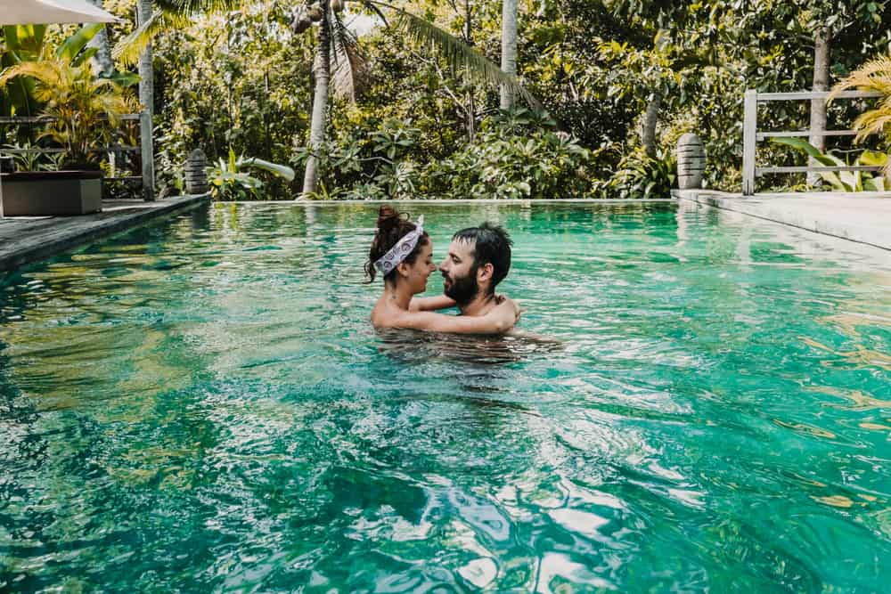 A couple braces one another in an infinity pool in the jungle.