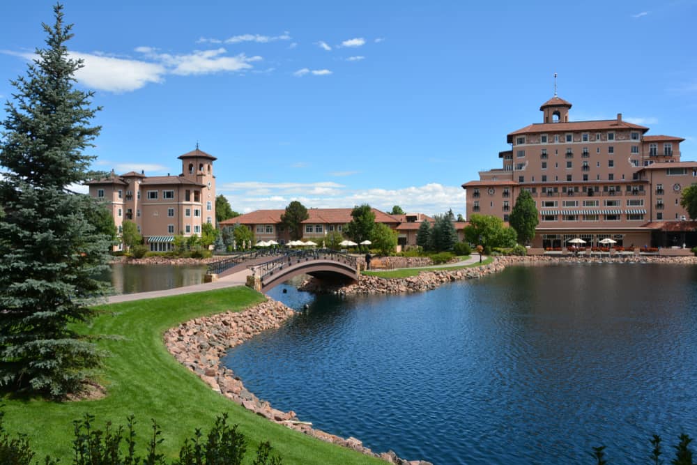 Deep blue lake in front of sprawling luxury resort buildings and blue sky above