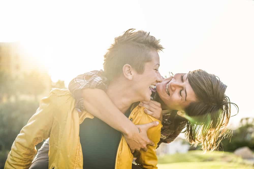 Married couple smiling and having fun together in the sun with one on the other's back