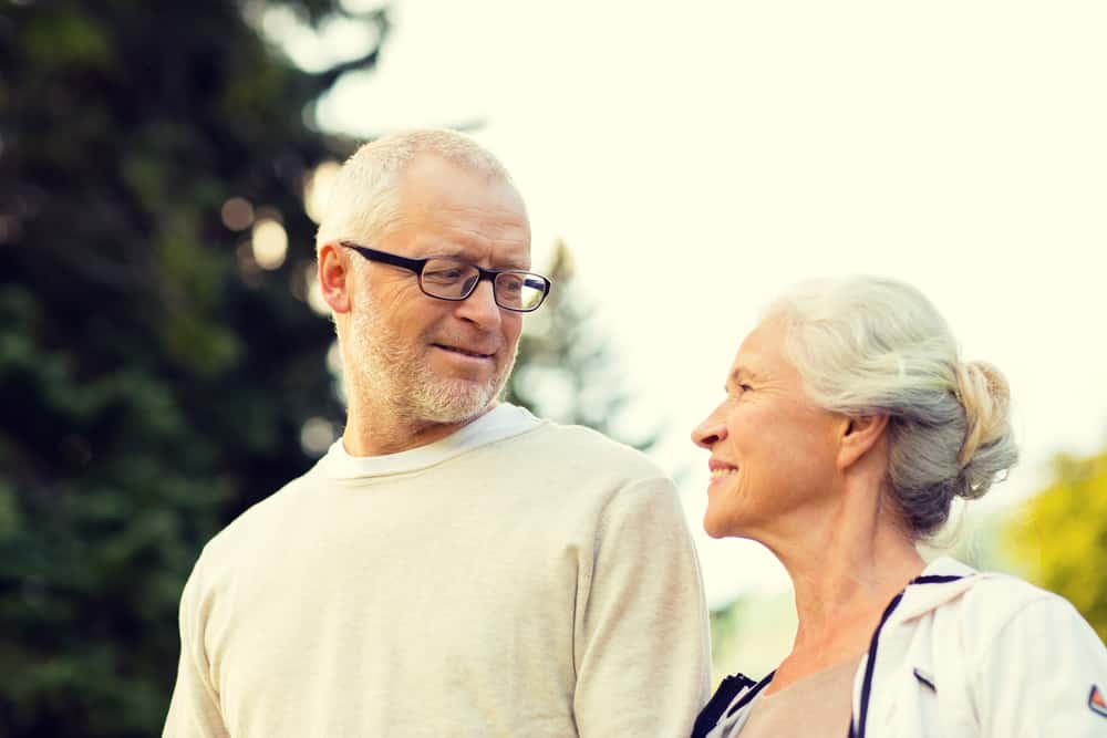 A mature couple in a park setting is walking and talking happily together on a clear day