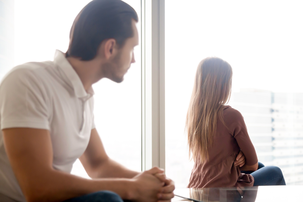 A woman stares out a window with her when to her partner without he has wrenched her trust in a relationship