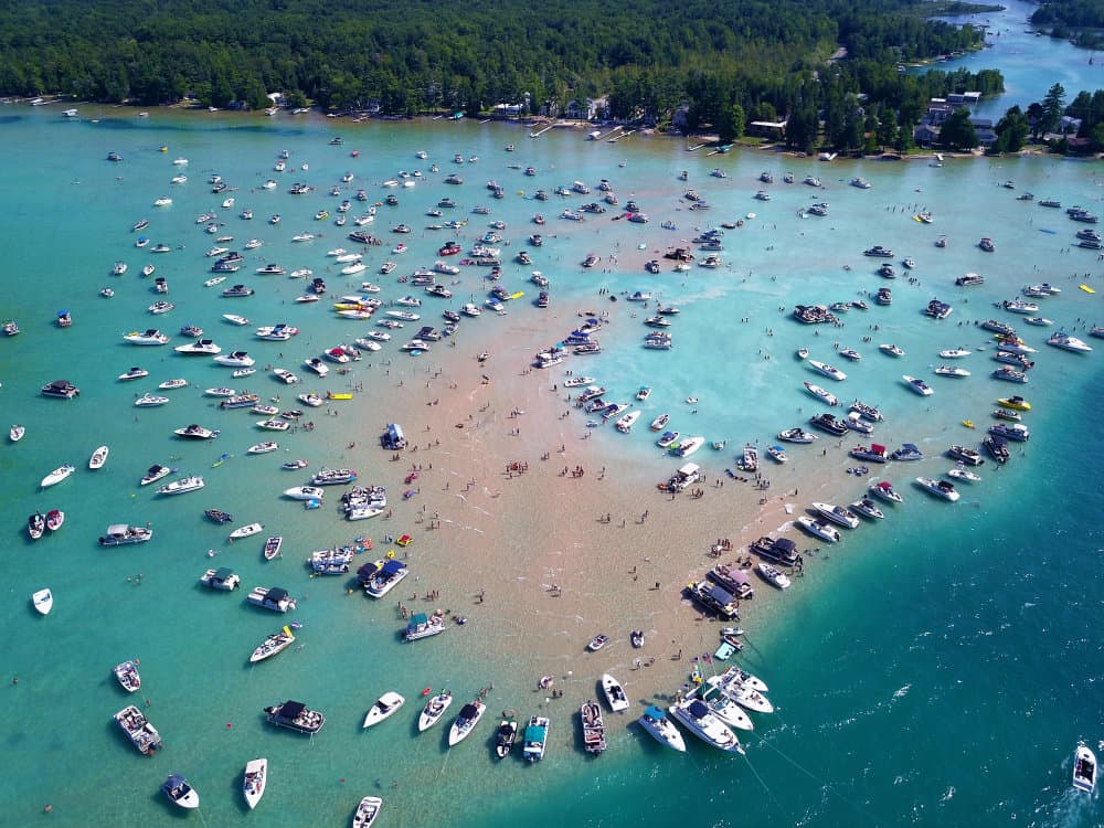 A turquoise lake is full of boats at a Michigan vacation destination
